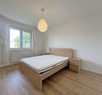 Rodinný dom v obci Láb, kľudná slepá ulica - Spálňa s posteľou, nočnými stolíkmi a podlahou s dreveným dekorom v rodinnom dome.