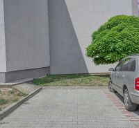 1-izbový byt v Šelpiciach s parkovacím miestom - Parkovisko pri budove na Suchovskej ulici v Šelpiciach s autom a zeleňou.
