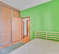 1-izbový byt v Šelpiciach s parkovacím miestom - Spálňa v 1-izbovom byte s podlahou s dreveným dekorom a zelenou stenou.