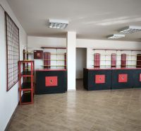 Prenájom obchodno-administratívneho priestoru , Šaľa  centrum - Obchodné priestory s pultom a policami, podlaha s dreveným dekorom, v čierno-červenej farbe.