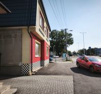 Prenájom obchodno-administratívneho priestoru , Šaľa  centrum - Obchodné priestory na ulici SNP v Šali s červeným autom na ceste.