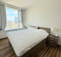 Na prenájom luxusný 3 izb. byt s garážou v Panorama City, Staré Mesto. - Izba s veľkým oknom, posteľou a podlahou s dreveným dekorom v 3-izbovom byte.