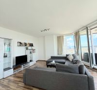 Na prenájom luxusný 3 izb. byt s garážou v Panorama City, Staré Mesto. - Obývacia izba s podlahou s dreveným dekorom, sedačkou a televízorom v 3-izbovom byte.