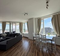Na prenájom luxusný 3 izb. byt s garážou v Panorama City, Staré Mesto. - Obývacia izba v 3-izbovom byte s podlahou s dreveným dekorom a veľkými oknami.