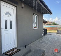 Predaj bungalovu - drevodom - Rodinný dom na ulici SNP v Čani má sivú fasádu a upravenú záhradu s bazénom.