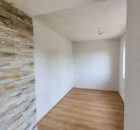 Rodinný dom po čiastočnej rekonštrukcii v Hriňovských Lazoch - Miestnosť v rodinnom dome s podlahou s dreveným dekorom a kamenným obkladom na stene.