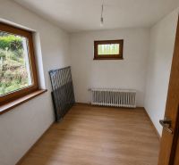 Rodinný dom po čiastočnej rekonštrukcii v Hriňovských Lazoch - Miestnosť v rodinnom dome s radiátorom a podlahou s dreveným dekorom.