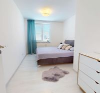 Moderný 3-izbový byt s veľkou terasou, garážou a nízkymi mesačnými nák - Svetlá spálňa s podlahou s dreveným dekorom, dvojposteľou a bielou komodou v 3-izbovom byte.