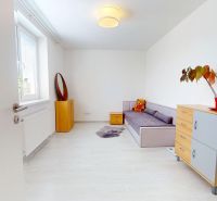 Moderný 3-izbový byt s veľkou terasou, garážou a nízkymi mesačnými nák - Izba v 3-izbovom byte s pohovkou, komodou a podlahou s dreveným dekorom.