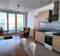 2-izbový byt s loggiou, vlastným kúrením a parkovaním - Veľký Šariš - Obývacia izba so sedačkami, kuchynskou linkou a podlahou s dreveným dekorom v 2-izbovom byte.