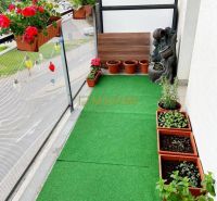 Veľký, slnečný a priestranný 3-izbový byt  - Balkón s kvetináčmi, umelým trávnikom a výhľadom na Vrakuňskú cestu v Bratislave.