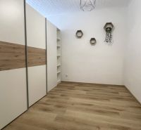 Prenájom 2-izbový byt s balkónom Martin – Podháj (41m2) - Izba v 2-izbovom byte s podlahou s dreveným dekorom a vstavanou skriňou.