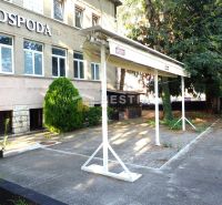 Reštaurácia s terasou na prenájom – centrum mesta - Obchodné priestory v Senici s parkoviskom, zeleňou a nápisom na budove.