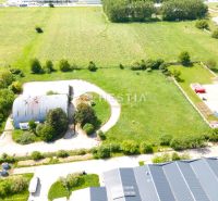 Skladový areál s pozemkom 10 000 m2 v priemyselnej zóne - Sklady a haly v Senici s okolitými zelenými plochami a priemyselnými budovami.