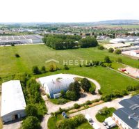 Skladový areál s pozemkom 10 000 m2 v priemyselnej zóne - Letecký pohľad na sklady a haly v Senici obklopené zeleňou a poľami.