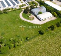 Skladový areál s pozemkom 10 000 m2 v priemyselnej zóne - Letecký pohľad na skladové a výrobné haly v Senici obklopené zelenými plochami.