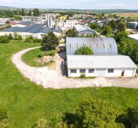 Skladový areál s pozemkom 10 000 m2 v priemyselnej zóne - Sklady a haly v Senici, obklopené trávnatou plochou a priemyselnou zástavbou.