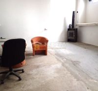 Hala na prenájom 400 m2 – priemyselná zóna - Priestor so starými sedačkami, stolom a kozubom vo výrobných priestoroch.