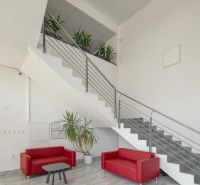 Kancelárie na PRENÁJOM | Vajnorská | TOP lokalita - Kancelárie s červenými sedačkami a schodiskom, podlaha s dlažbou, rastliny v kvetináčoch.
