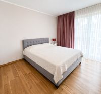 Priestranný 4-izbový byt s výhľadom na mesto - Nová Koliba - Spálňa s veľkou posteľou, svetlými stenami a podlahou s dreveným dekorom v 4-izbovom byte.
