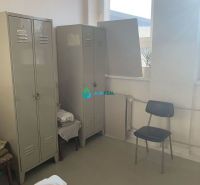 Výrobné a skladové priestory na prenájom. - Skrinky, stolička, radiátor a okno vo výrobných priestoroch s podlahou s dreveným dekorom.