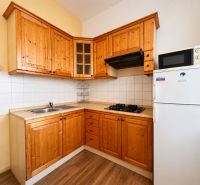 Na prenájom 1 izbový byt po rekonštrukcii – Banská Bystrica/centrum - Kuchyňa v 1-izbovom byte s drevenými skrinkami a podlahou s dreveným dekorom.