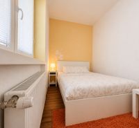 Na prenájom 1 izbový byt po rekonštrukcii – Banská Bystrica/centrum - Spálňa v 1-izbovom byte s podlahou s dreveným dekorom a oranžovým kobercom.