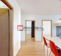 3D OBHLIADKA - Priestranný 3-izbový byt v Senci s lodžiou a klimatizác - Interiér 3-izbového bytu s podlahou s dreveným dekorom, stolom a červenými stoličkami.