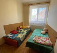 Predaj 3 izbového bytu vo Vyhniach - Izba s dvoma posteľami, drevená podlaha, okno s bielou záclonou v 3-izbovom byte.