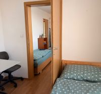 4-izbový byt, Bratislava/Nové Mesto, ulica Nová Rožňavská - Spálňa v 4-izbovom byte s podlahou s dreveným dekorom, posteľou a kancelárskou stoličkou.