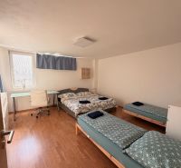 4-izbový byt, Bratislava/Nové Mesto, ulica Nová Rožňavská - Spálňa v 4-izbovom byte s trojicou postelí a podlahou s dreveným dekorom.