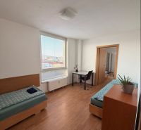4-izbový byt, Bratislava/Nové Mesto, ulica Nová Rožňavská - Izba v 4-izbovom byte s dvoma posteľami, písacím stolom a podlahou s dreveným dekorom.