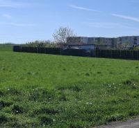 Stavebný pozemok 1212m² v obci Šelpice - Pozemok na bývanie na Slnečnej ulici v Šelpiciach s budovami v pozadí.