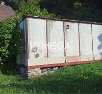 Na predaj pozemok/záhradka v záhradkárskej osade Poniklec Humenné - Starší sklad v záhrade ulice v Humennom, obklopený zeleňou a rastúcou trávou.