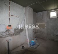 Na predaj - Dom s veľkým pozemkom v Pakostove - Nedokončená miestnosť v rodinnom dome s nedokončenými stenami a stavebným materiálom.