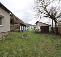 Na predaj - Dom s veľkým pozemkom v Pakostove - Záhrada pri rodinnom dome na ulici v Pakostove, so staršou drevenou kôlňou a trávnikom.