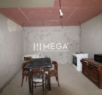 Na predaj - Dom s veľkým pozemkom v Pakostove - Nedokončená kuchyňa v rodinnom dome s jednoducho zariadenými staršími spotrebičmi a nábytkom.