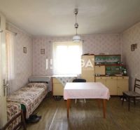 REZERVOVANÉ - Dom s krásnym pozemkom v Zbudskej Belej - Izba v rodinnom dome s tapetami, stolom, posteľou, vitrínou a podlahou s dreveným dekorom.