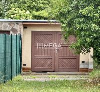 Na predaj garáž s pozemkom na sidl. IIA v meste Humenné - Garáže na ulici Osloboditeľov v Humennom s drevenou bránou, obklopené zeleňou.