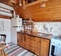 VÝRAZNE ZNÍŽENÁ CENA!!!  CHATA v Rekreačnej oblasti Domaša - Kuchyňa v chate s podlahou s dreveným dekorom, drevenými skrinkami a jedálenským stolom.