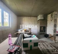Na predaj uzavretá hrubá stavba RD, Svinica, Košice - okolie - Interiér rodinného domu s nedokončenými stenami, krbom a staveniskovým materiálom.