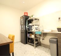 NA PRENÁJOM: Kancelárske priestory + 3-izbový apartmán – Košice - Kuchyňa v budove s pracovnou linkou, chladničkou a stolom s čalúnenou stoličkou.