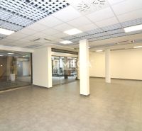 NA PRENÁJOM OBCHODNÝ PRIESTOR 96 m² – BEZ DEPOZITU, TOP CENA - Priestranné obchodné priestory s mriežkovým stropom a šedou podlahou s dreveným dekorom.