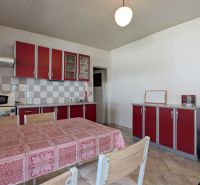 TRADIČNÝ DOM V SRDCI TAJOVA, 893 M2, TAJOV - Kuchyňa v rodinnom dome s červenými skrinkami a jedálenským stolom.