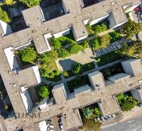 2 - IZBOVÝ BYT | BRATISLAVA III | VAJNORSKÁ  - Letecký pohľad na bytový dom obklopený stromami a parkovacím miestom v Bratislave.