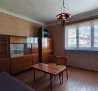 Znížená cena!!! Vidiecky dom v obci Olováry v okrese Veľký Krtíš. - Izba v Rodinnom dome s nábytkom, kreslami a stolom, s dreveným dekorom podlahy.