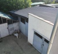 Váš nový rodinný prístav v obci Iža: Priestor, kľud a čerstvá úroda z  - Rodinný dom v Nitre s garážou, betónovým dvorom a zeleňou na pozadí.