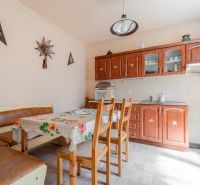 NA PREDAJ RODINNÝ DOM S POZEMKOM O VÝMERE 1003m2 - Kuchyňa v Rodinnom dome so stolom, stoličkami, kuchynskou linkou a dekoračnými prvkami na stene.