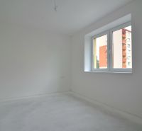 3-izbový byt s balkónom v Rezidencii Madone - Prázdna izba v 3-izbovom byte s bielymi stenami a veľkým oknom.