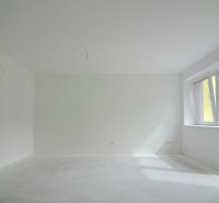 3-izbový byt s balkónom v Rezidencii Madone - Svetlá miestnosť v 3-izbovom byte s veľkým oknom a bielymi stenami.